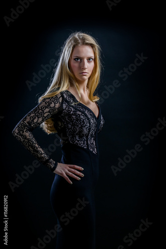 blonde girl on a black background in a dark guipure dress