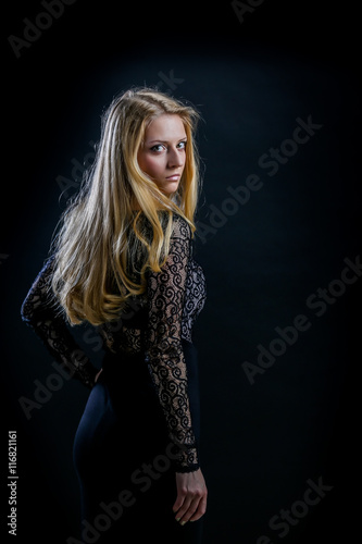 blonde girl on a black background in a dark guipure dress