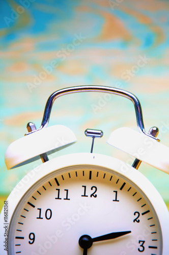White alarm clock isolated on colorful wooden background