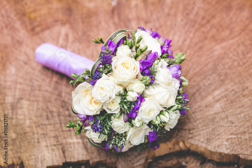 Wedding bouquet with white and violet flowers on nature wooden background. © at_shoots