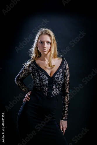 blonde girl on a black background in a dark guipure dress © latinist