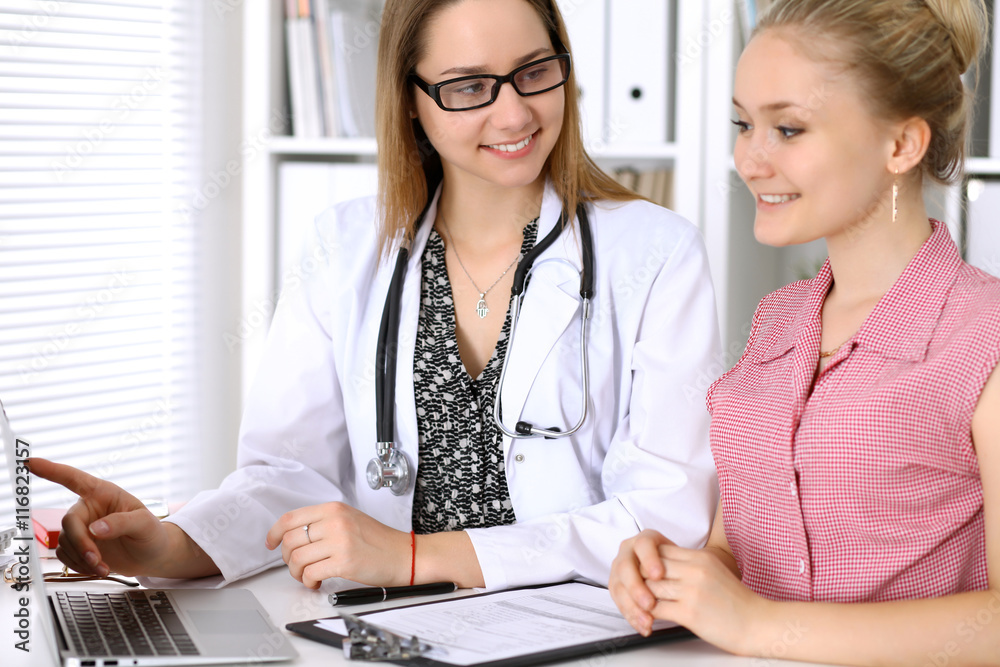 Doctor discussing confidental medical history with his patient and pointing at monitor computer Doctor discussing confidental medical history with his patient and pointing at monitor computer