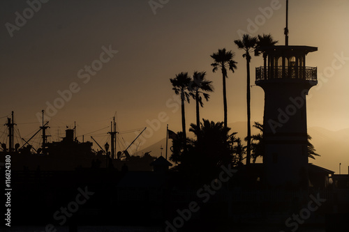 Silhouette of a light house and ship in the background