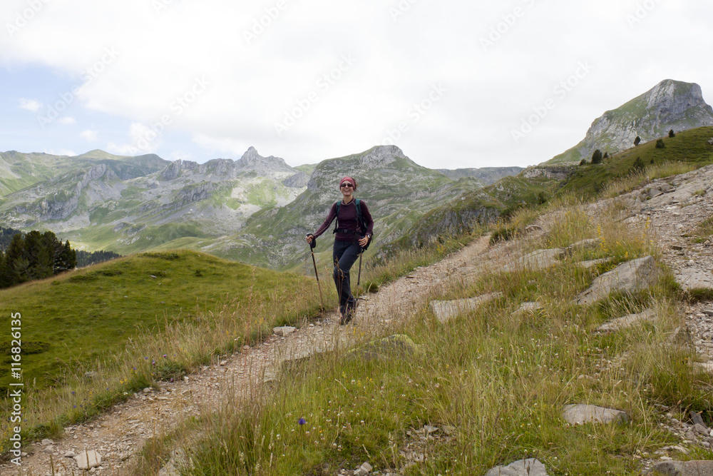 happy girl hiking the mountains in Pyrenees, France with her hiking sticks