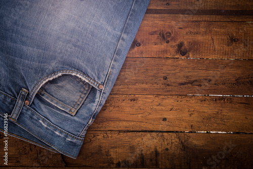 old blue jeans that is a bit torn on wood background