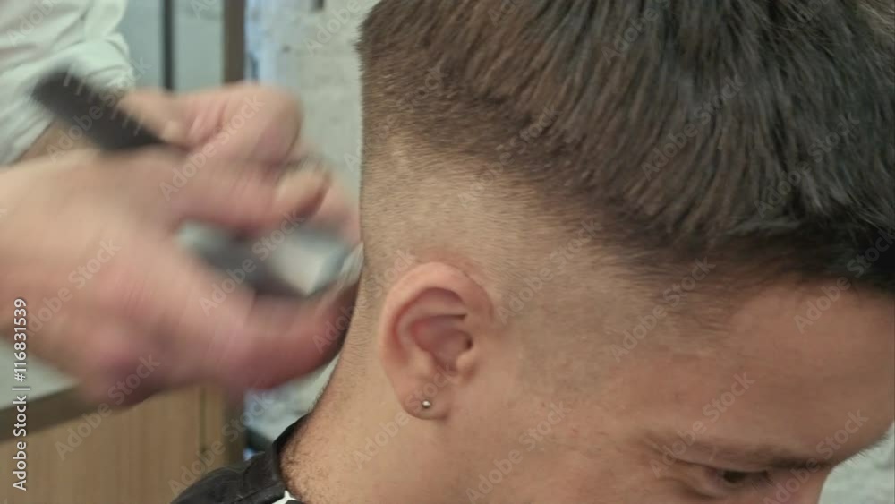 Hairdresser cutting with trimmer hair of man client at beauty parlour Hairdresser cutting with trimmer hair of man client at beauty parlour