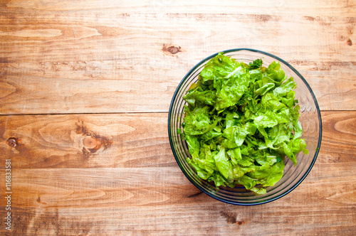 Fresh green salad in a bowl on a wooden background