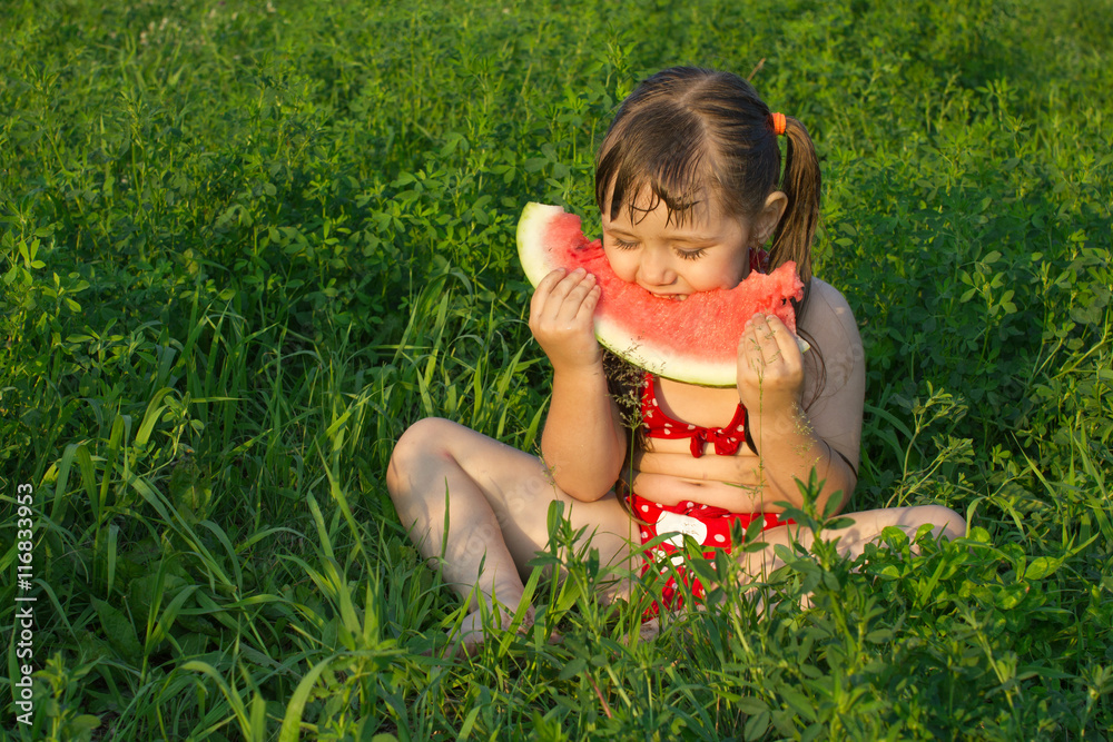 little white girl children sit on grass and hold watermelon little white girl children sit on grass and hold watermelon