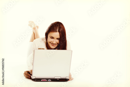 Smiling young woman lying at a floor and she working with laptop © Sławomir Fajer