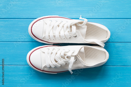 A pair of white canvas shoes on a blue wooden