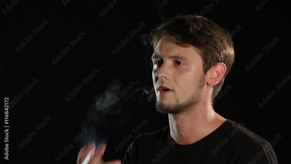 Man smokes a cigarette in a dark room. Black. Close up Man smokes a cigarette in a dark room. Black. Close up