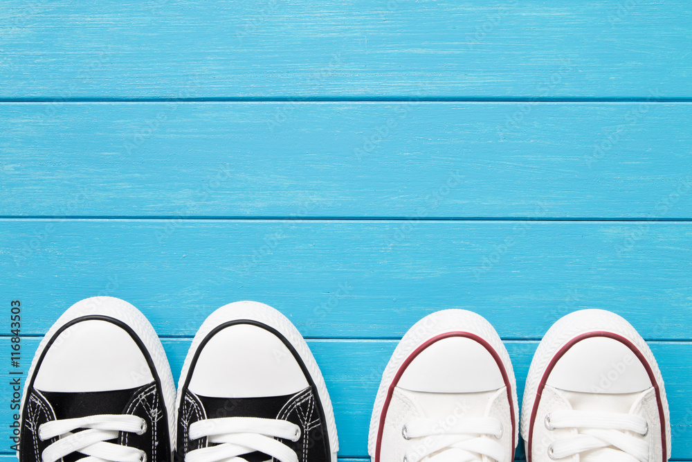 Two pairs of canvas shoes on a blue wooden