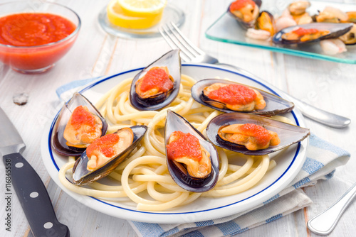 spaghetti and mussels with tomato sauce in white china