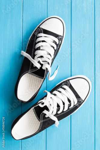 A pair of black canvas shoes on a blue wooden