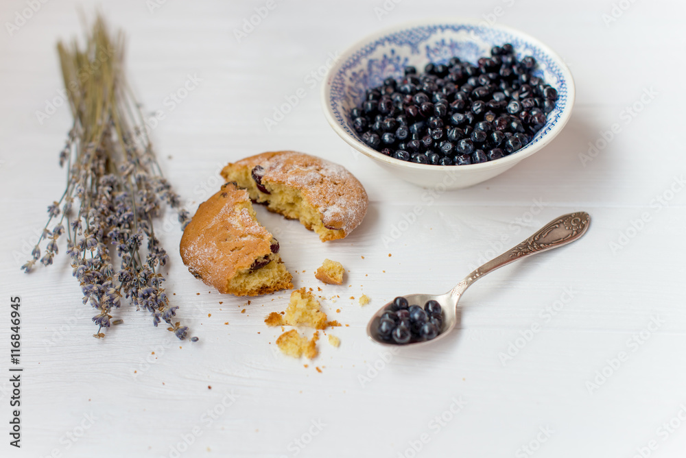 A flat lay of a blueberry muffin , blueberry bowl and flowers of lavender on a white background A flat lay of a blueberry muffin , blueberry bowl and flowers of lavender on a white background