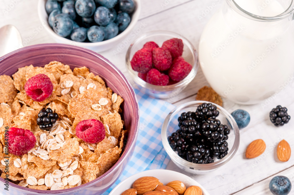 healthy breakfast with cornflakes berries, milk and almond nuts on wooden table healthy breakfast with cornflakes berries, milk and almond nuts on wooden table