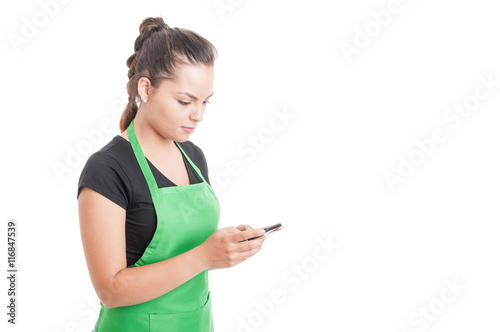 Attractive young seller typing a message on cellphone