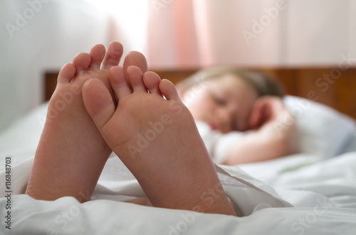 little girl's feet who sleeps inher bed closeup