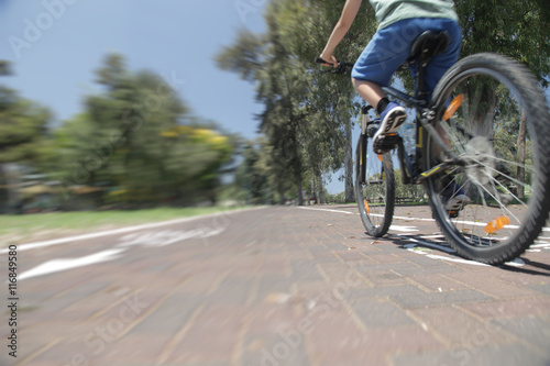 Boy riding bike on bicycle lane in park. Speed motion blur.