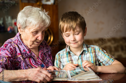 Elderly woman with her little grandson looking album