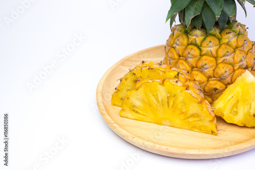 Pineapple fruit cut on wooden plate on white background