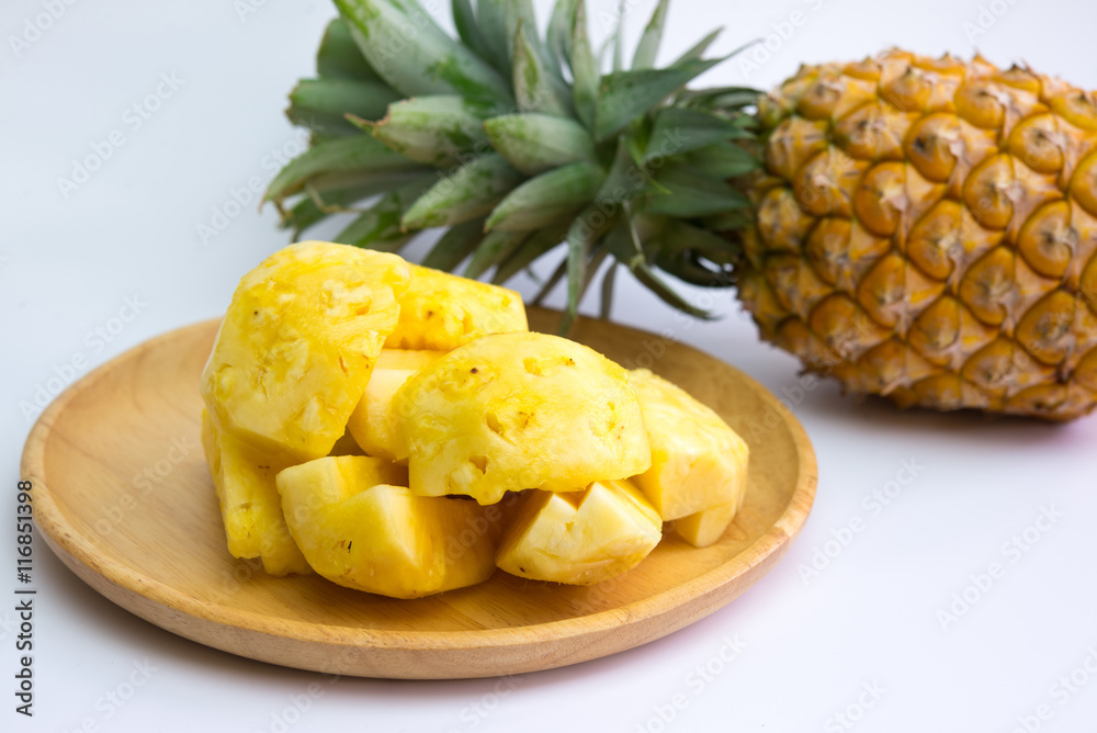 Pineapple fruit cut on wooden plate on white background Pineapple fruit cut on wooden plate on white background