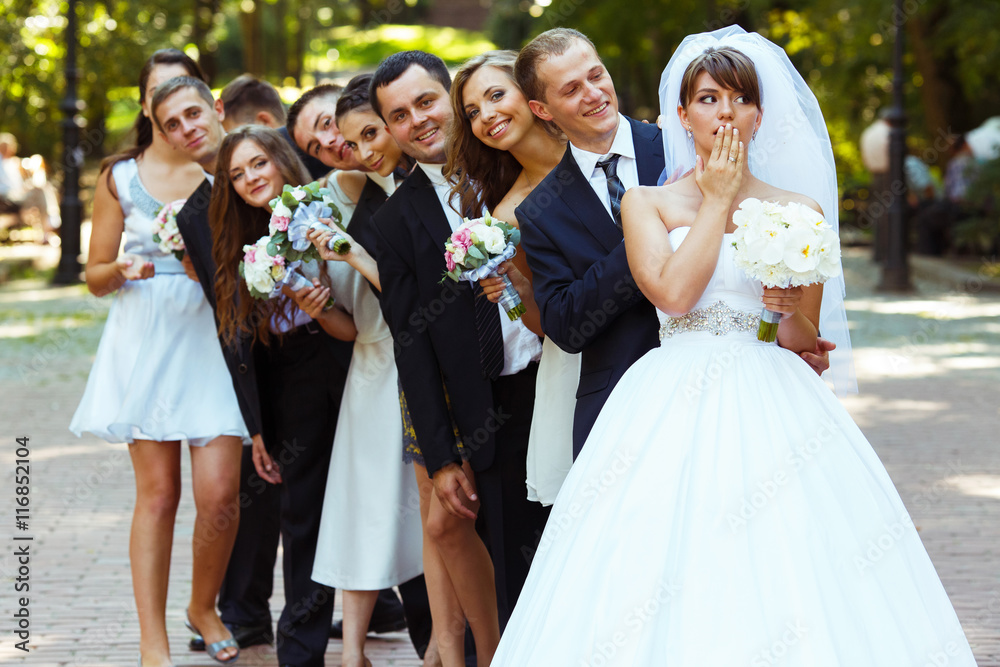 Bride grimaces while posing with friends on the park path