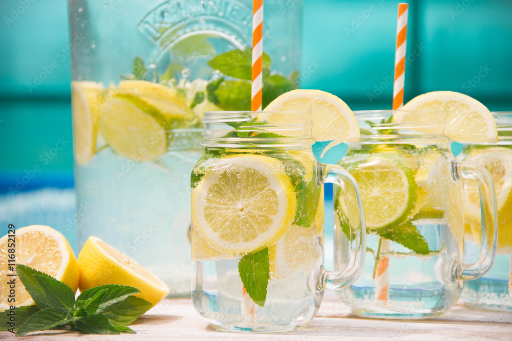 Lemonade drink in the jug on the white table near the pool