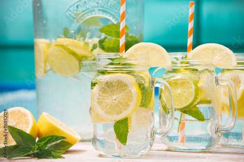 Lemonade drink in the jug on the white table near the pool