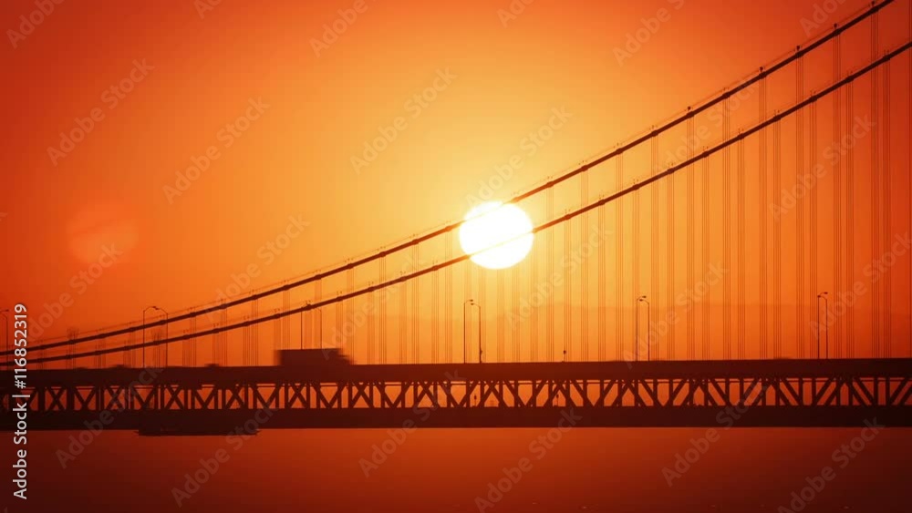 The Sun rising from behind the Bay Bridge in San Francisco.