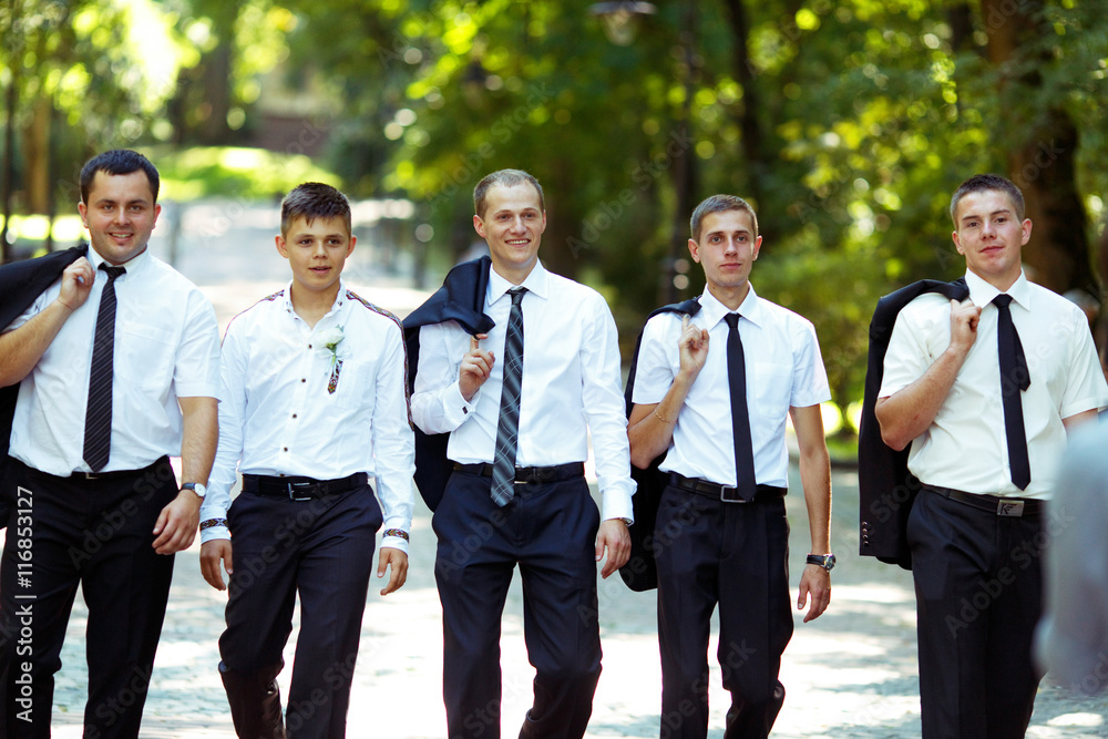 Groom and groomsmen walk proud holding their jackets over should Groom and groomsmen walk proud holding their jackets over should