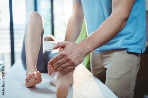 Male physiotherapist giving foot massage to female patient photo