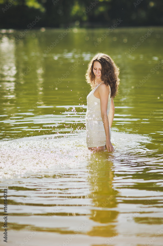 Fototapeta premium Portrait of a girl in a short white dress standing waist-deep in