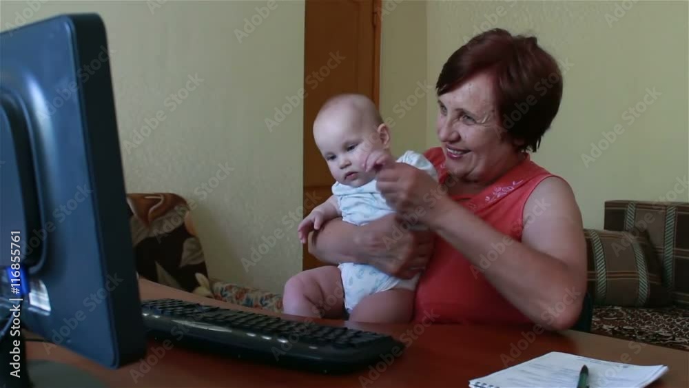 An elderly woman is calling on the computer and the baby shows An elderly woman is calling on the computer and the baby shows