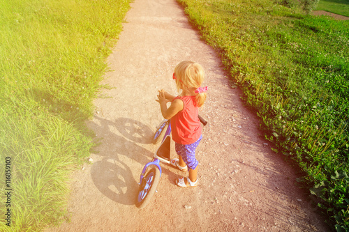 little girl riding runbike in summer photo