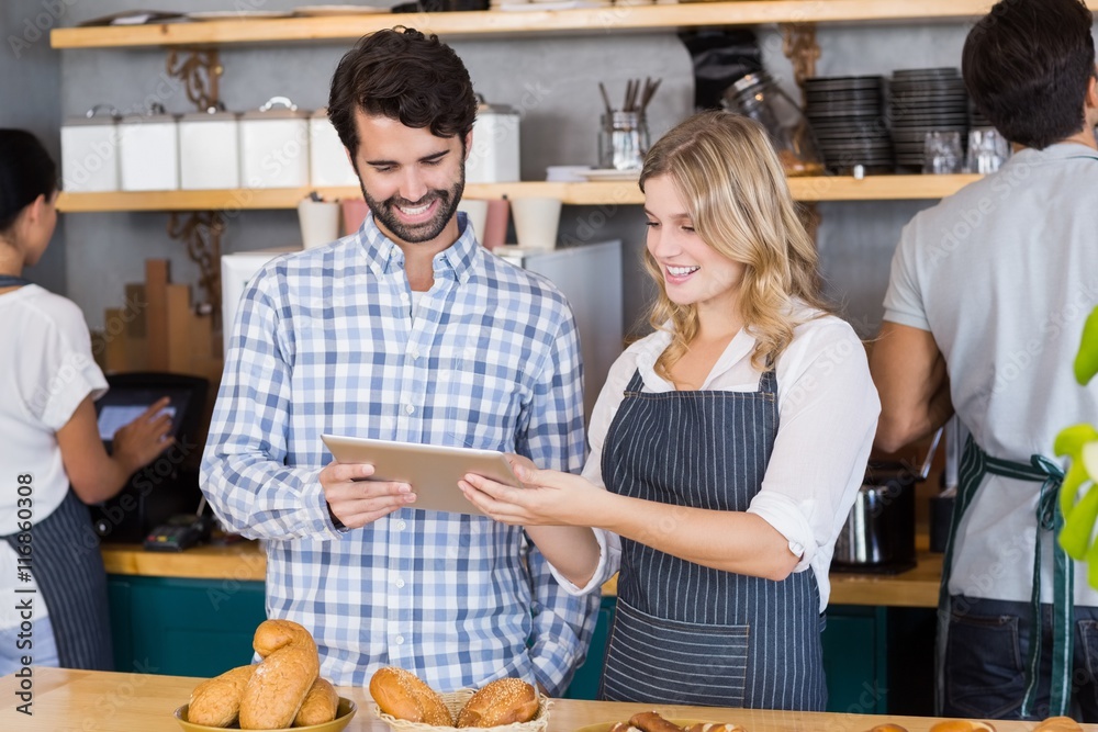 Man and waitress standing at counter using digital tablet Man and waitress standing at counter using digital tablet
