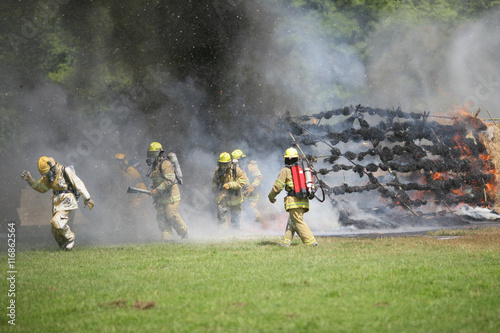 Fire fighters escape from burning structure. photo