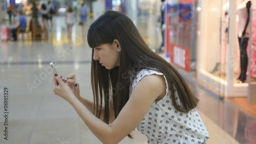 Young woman playing Pokemon GO indoor at shopping center, using smart phone. Girl play the popular smartphone game - catching pokemon in hypermarket mall photo