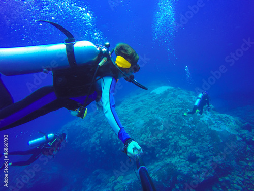 Underwater scuba diving selfie shot with selfie stick. Deep blue sea. Wide angle shot.