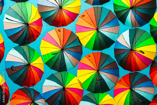 Colorful umbrella with colors of rainbow in the blue clear sky. Conceptual bright background.