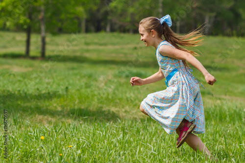 Fototapeta Child girl running at green meadow