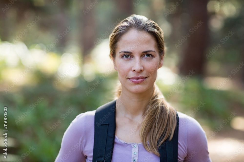 Confident woman standing in forest carrying backpack Confident woman standing in forest carrying backpack