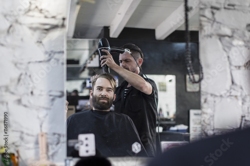 Barber blow-drying hair of a customer