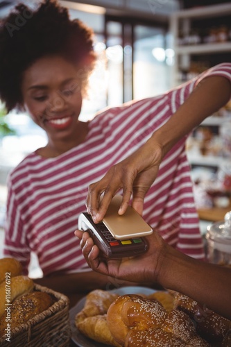Woman paying bill through smartphone using nfc technology