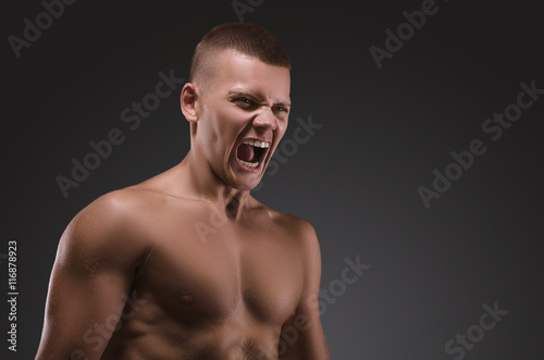 Healthy muscular young man screaming. Sport portrait. Emotion.