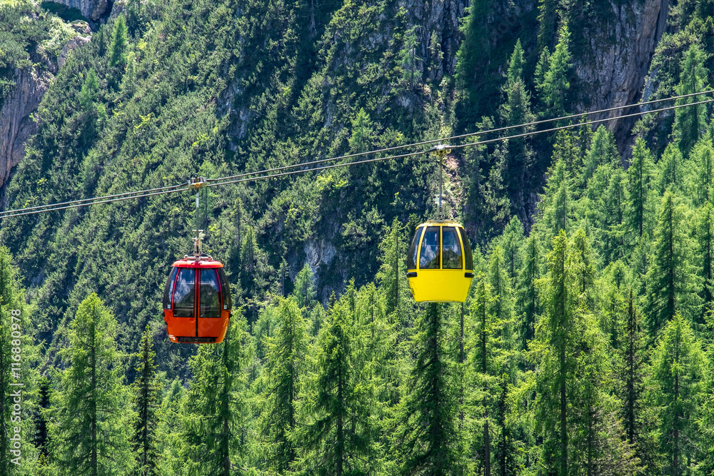 Red and yellow cable car over the green forest