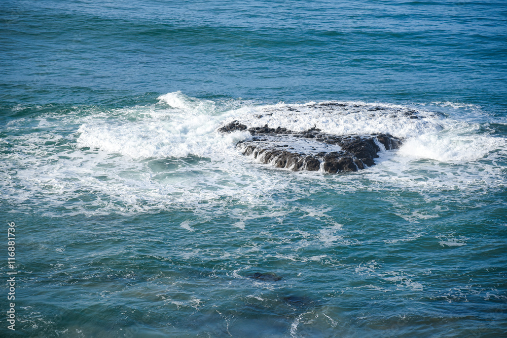 Fototapeta premium water wave hitting giant rock in the sea