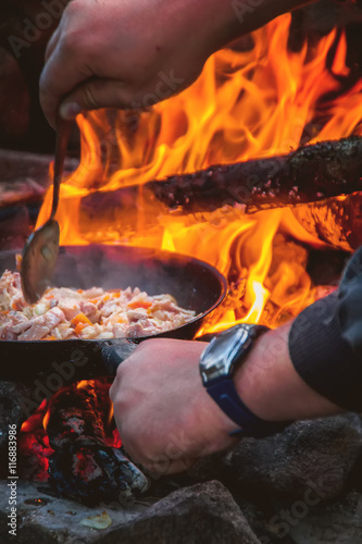 The man cooking food on a fire.
