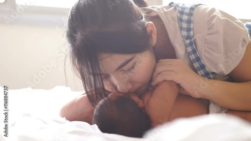 asian young pretty mother kissing her little baby with love