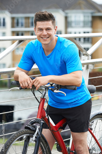 Young Man Cycling Next To River In Urban Setting © highwaystarz